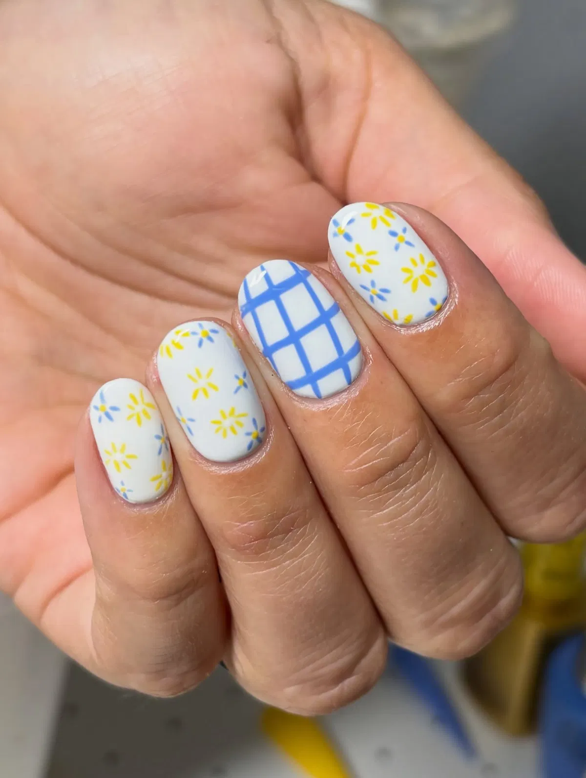 White nails with blue grid and yellow-blue floral scatter