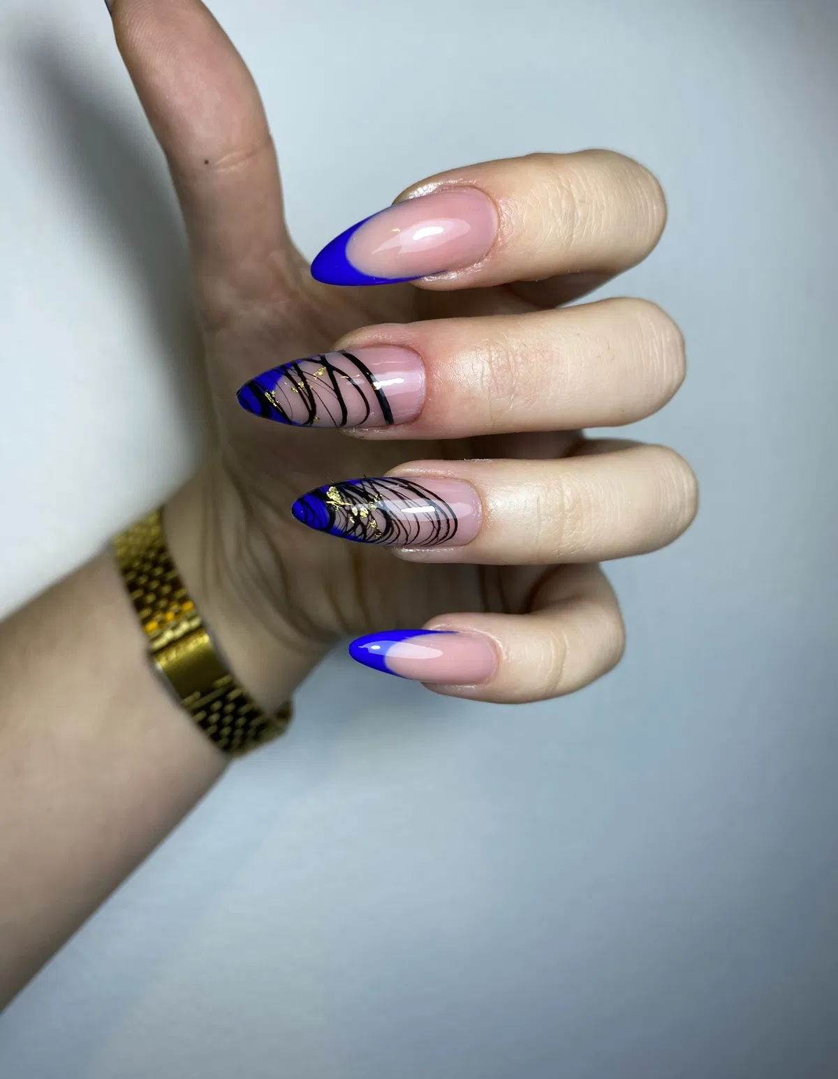 Bright blue French tips with black line art and gold flecks
