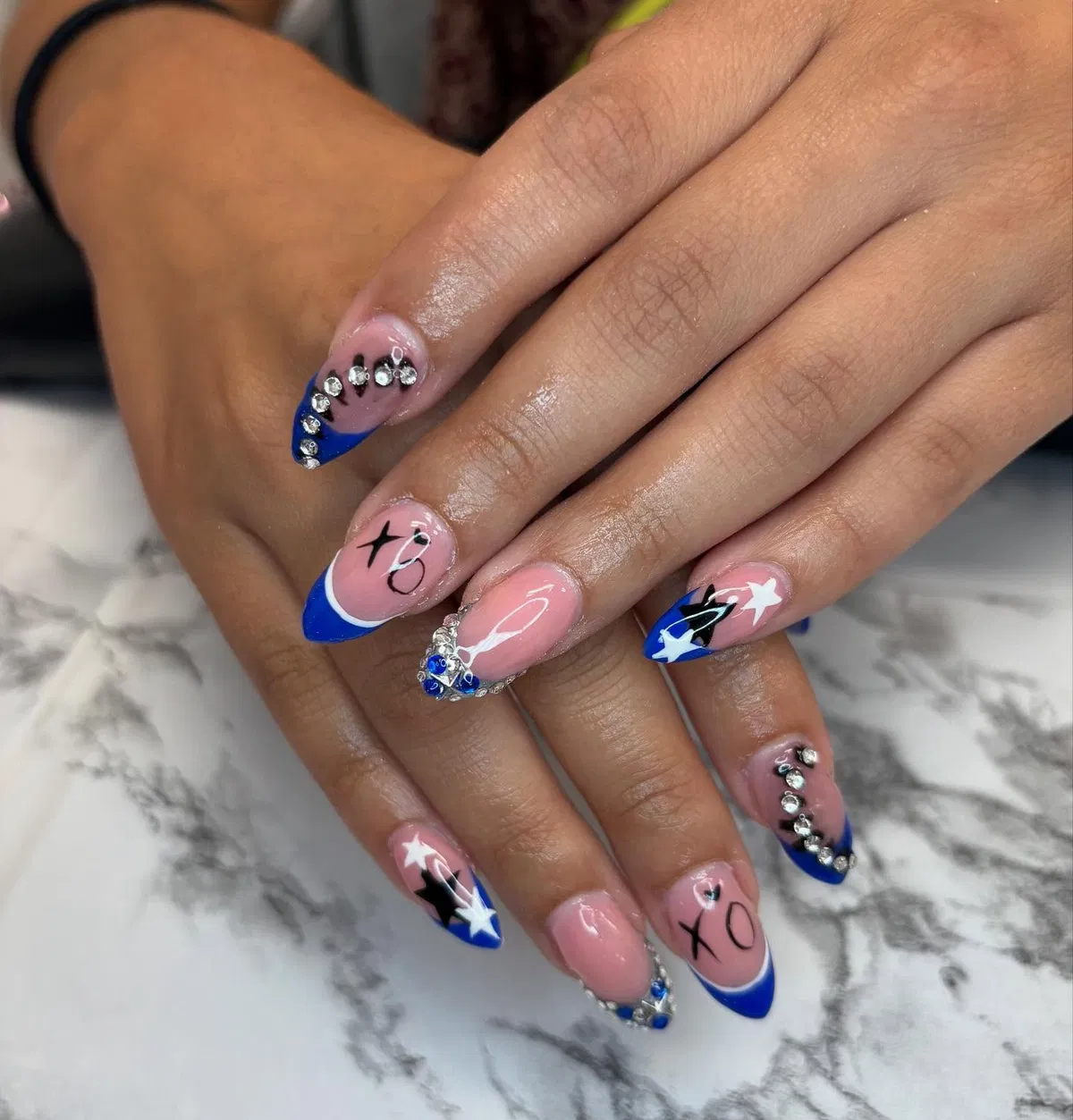 Blue French tips with rhinestones, stars, and XO lettering