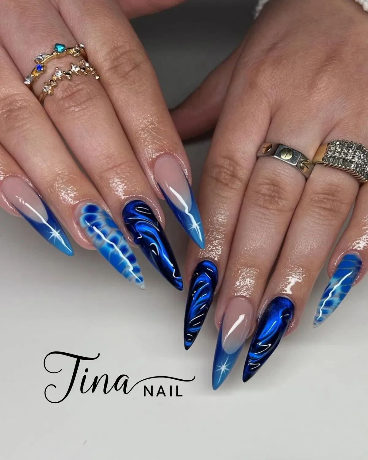Blue French tips with dark swirls and starbursts