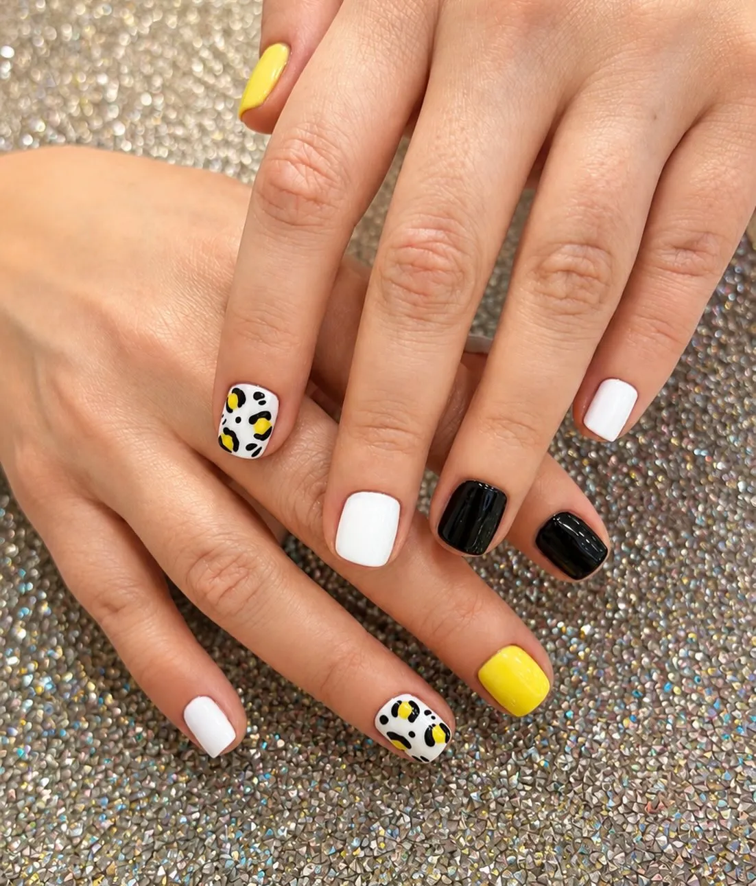 Short glossy set with yellow solids and spotted accent nails