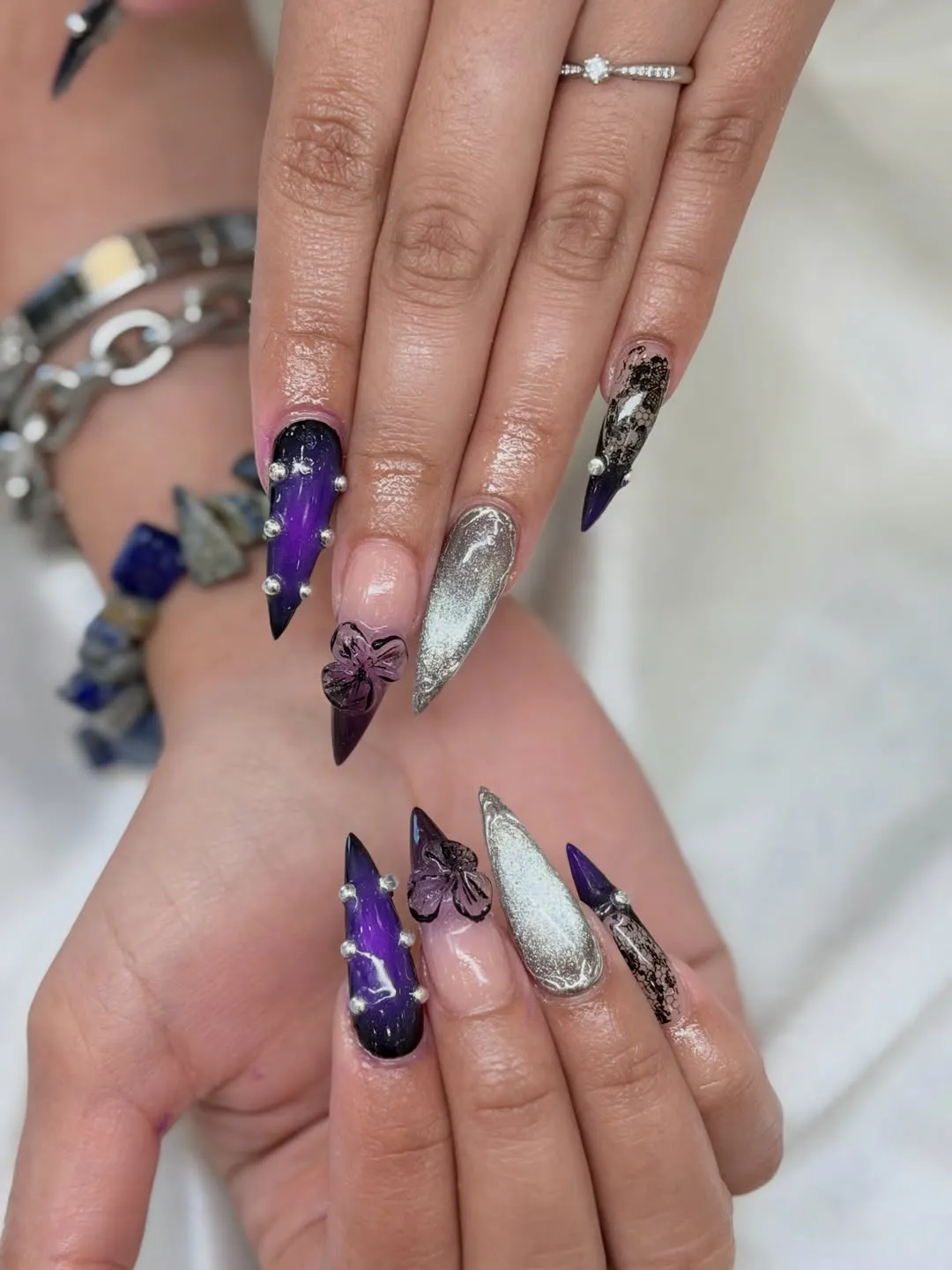 Purple-black stiletto nails with studs and lace accents