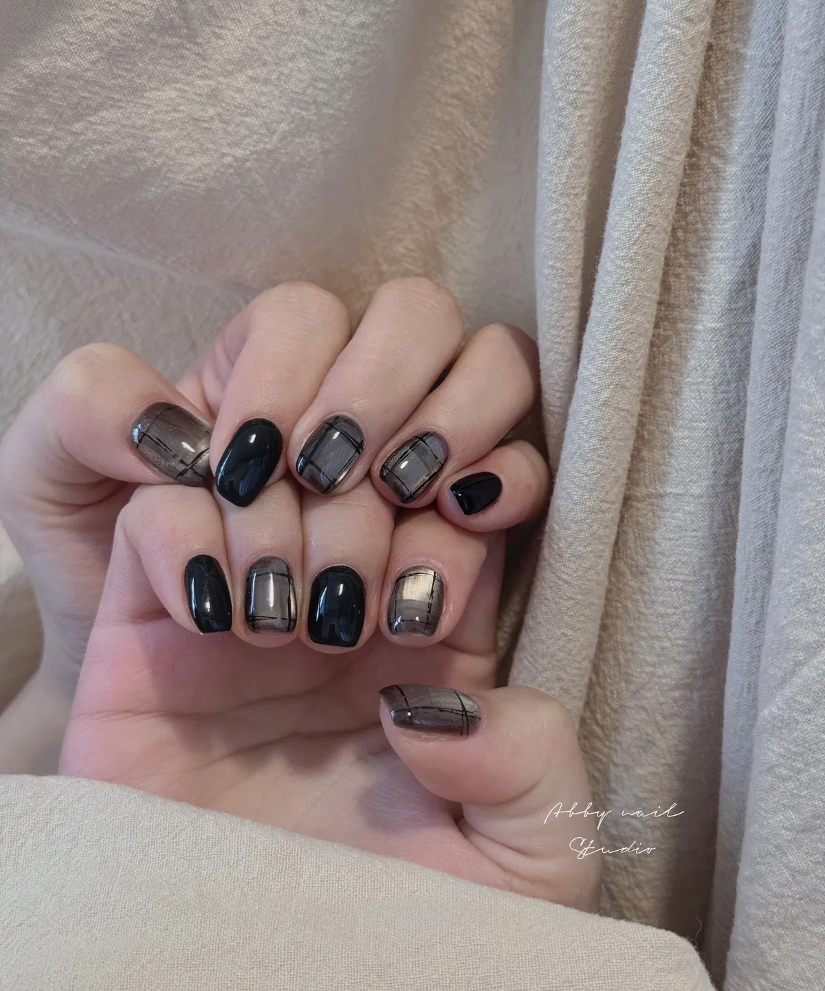 Glossy black nails mixed with translucent gray plaid grid accents