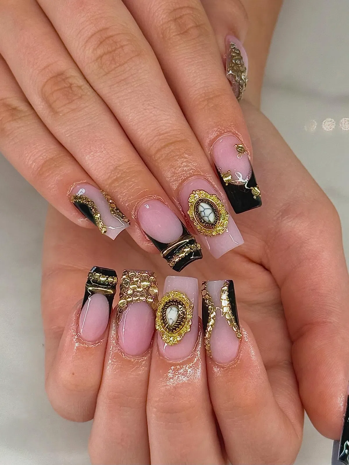 Square nude-and-black tips with ornate gold framed centerpiece accents