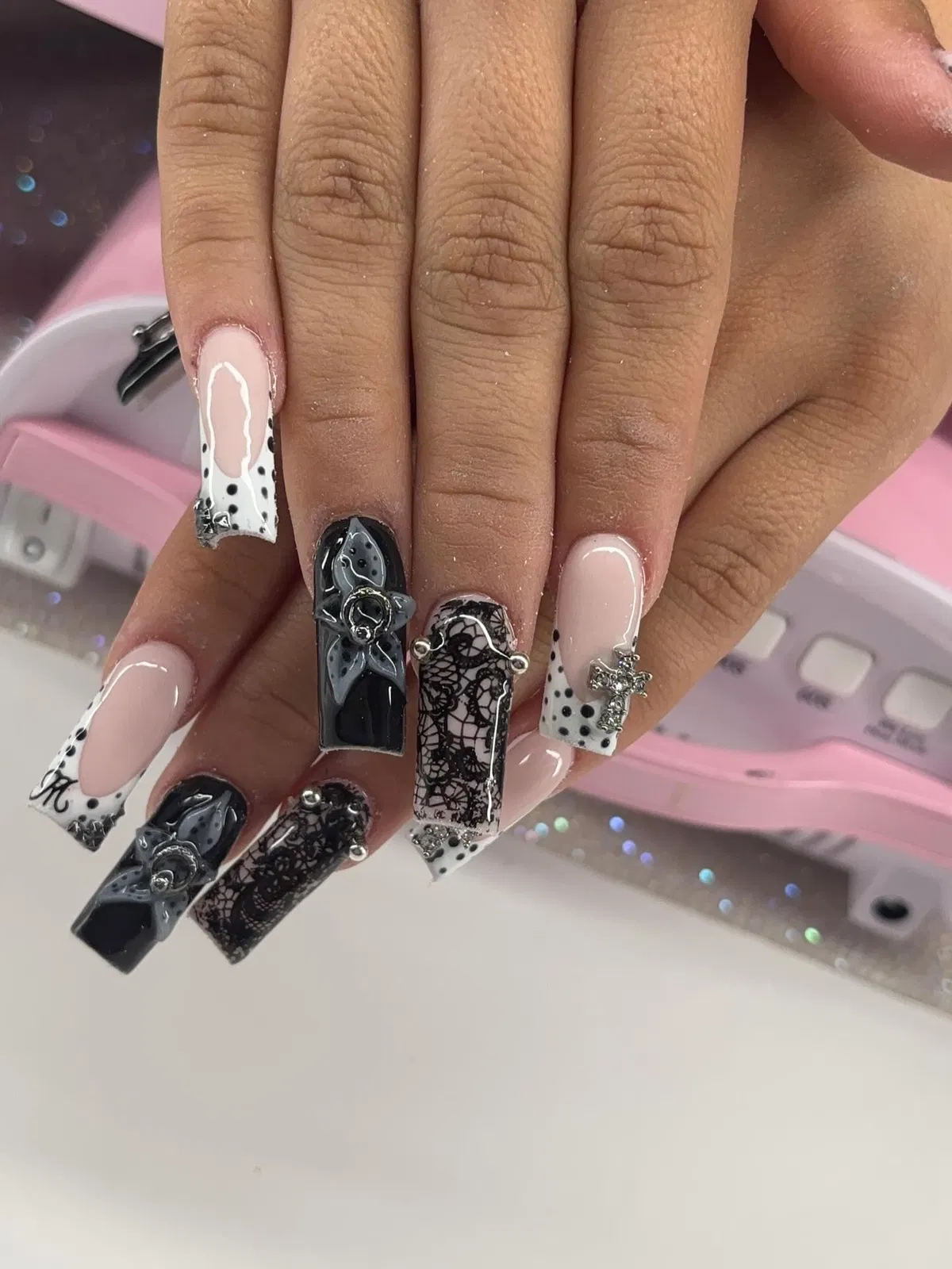 Polka-dot French tips mixed with black lace-style accents and a silver cross charm