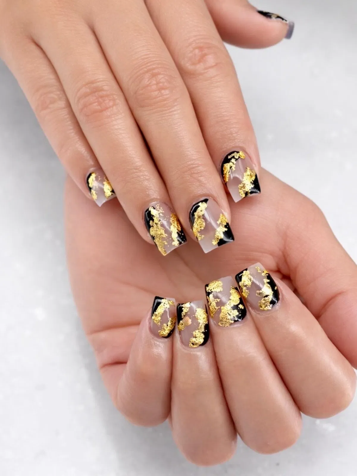 Nude square nails with black corners and gold foil accents