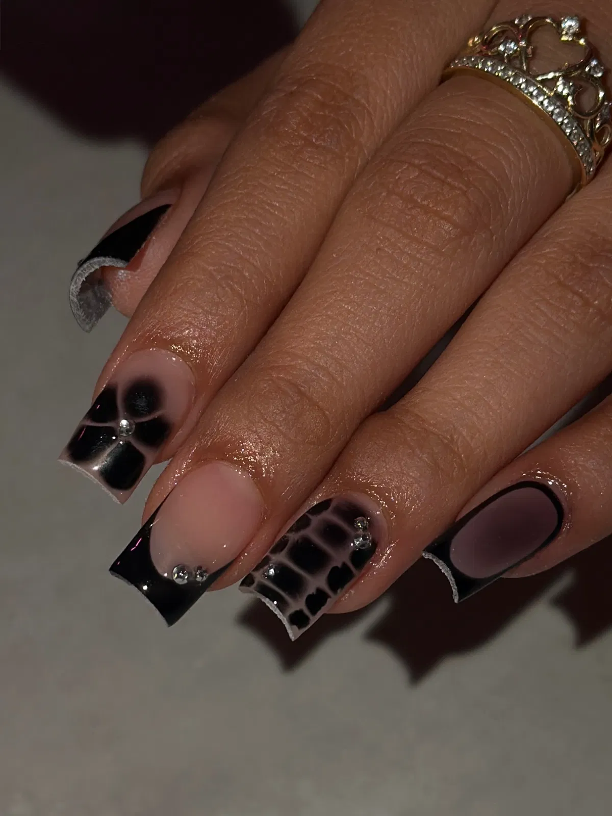 Black French tips with airbrushed florals, grid pattern, and gem accents