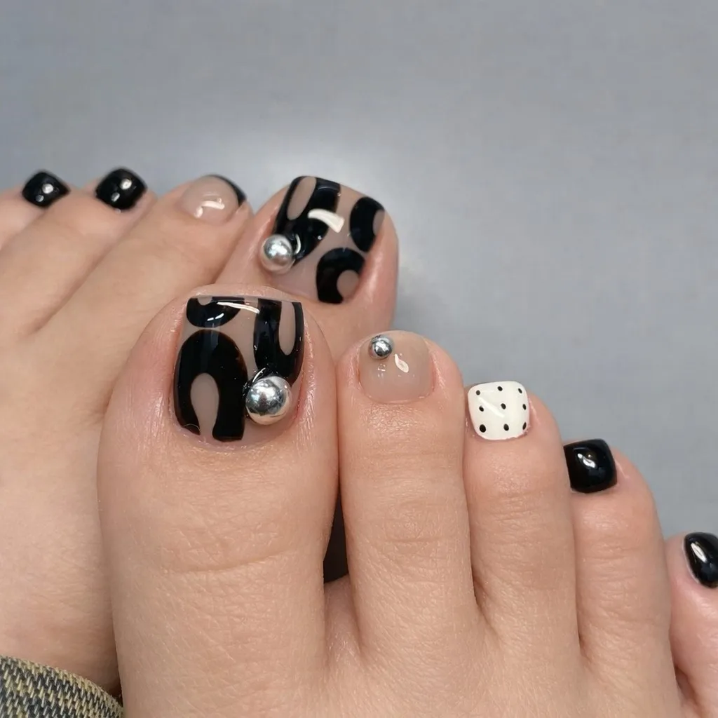 Abstract black-on-nude big toes with silver studs