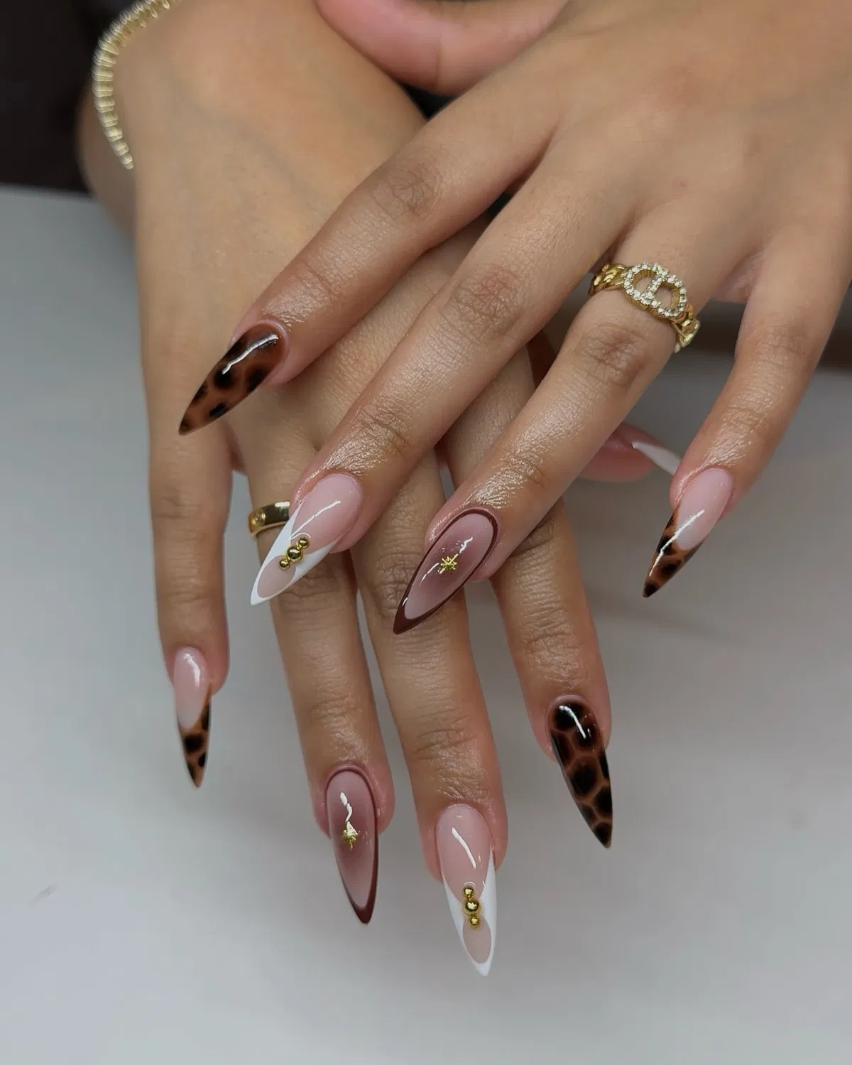 Stiletto French tips with brown borders, spots, and gold star accents
