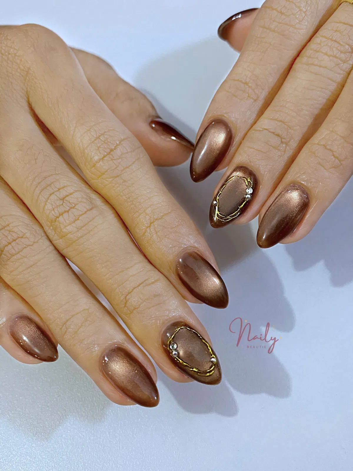 Metallic bronze-brown nails with raised gold frames and gems