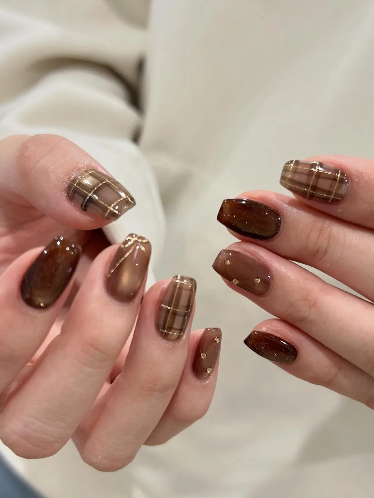 Dark brown glitter nails with metallic grid plaid and small gold studs