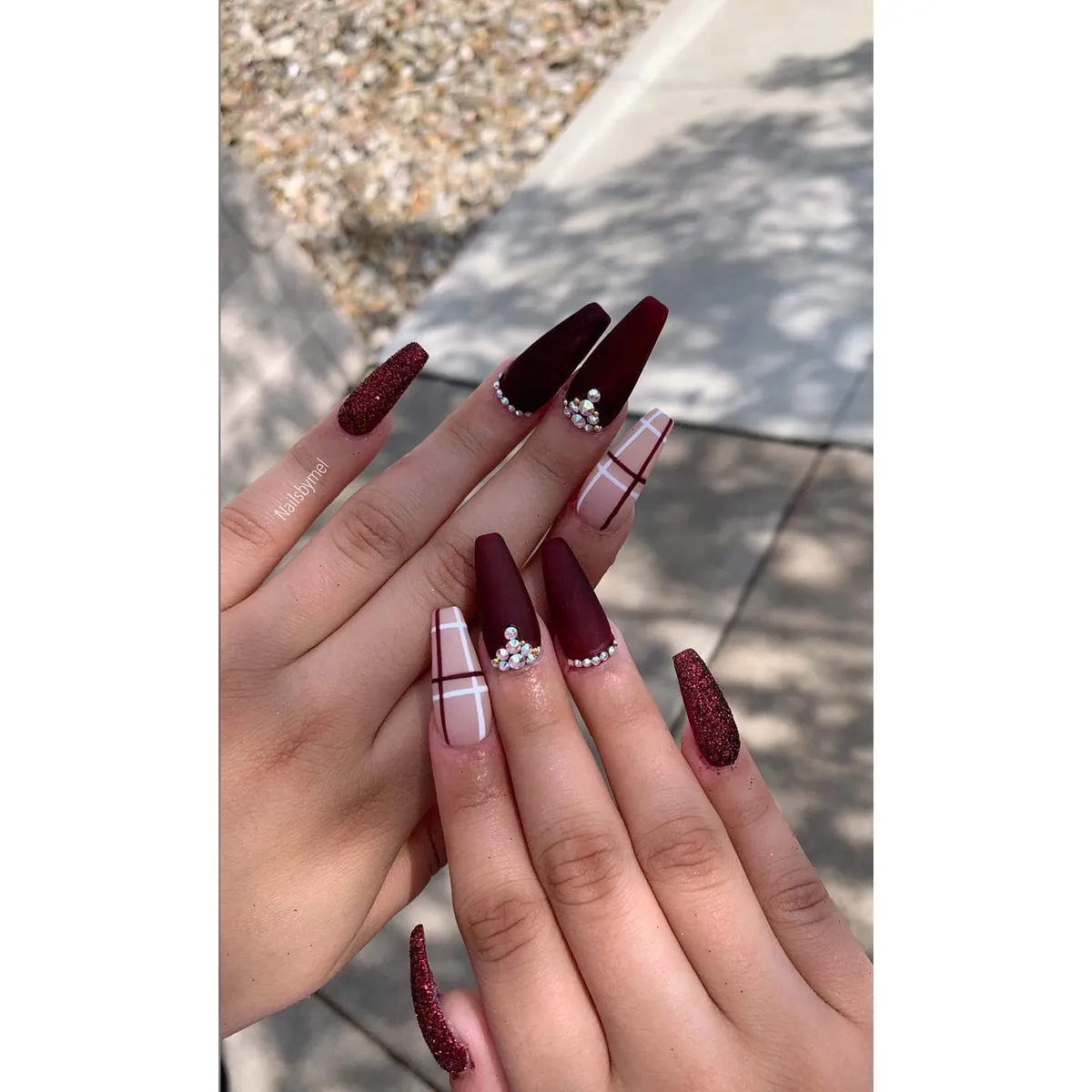 Matte burgundy coffin nails with glitter accents, plaid details, and rhinestones