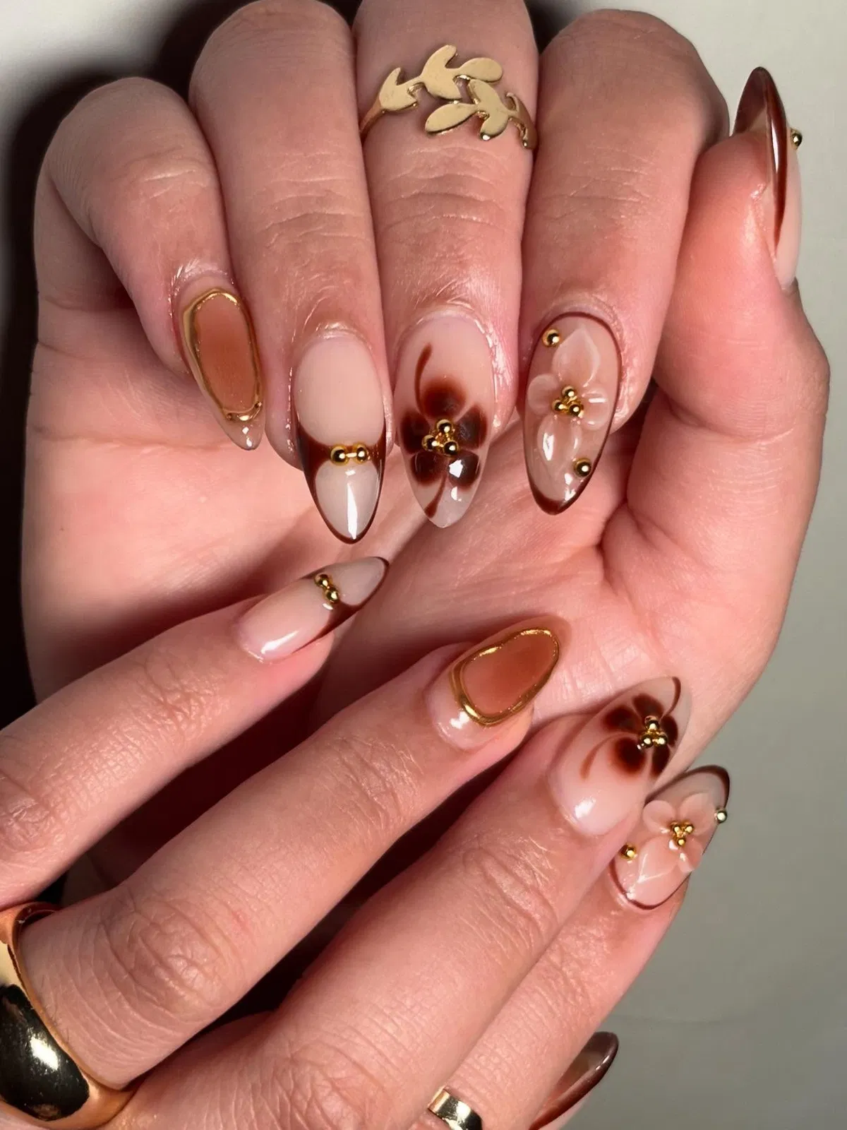 Nude-and-brown French tips with gold studs and 3D flowers