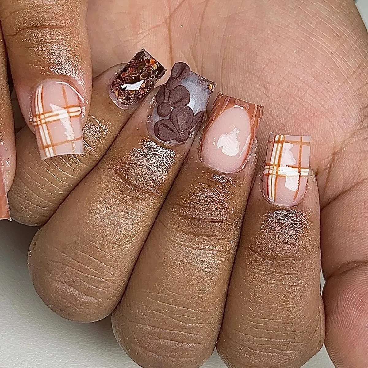 Nude base with orange plaid, glitter, and brown leaf accents