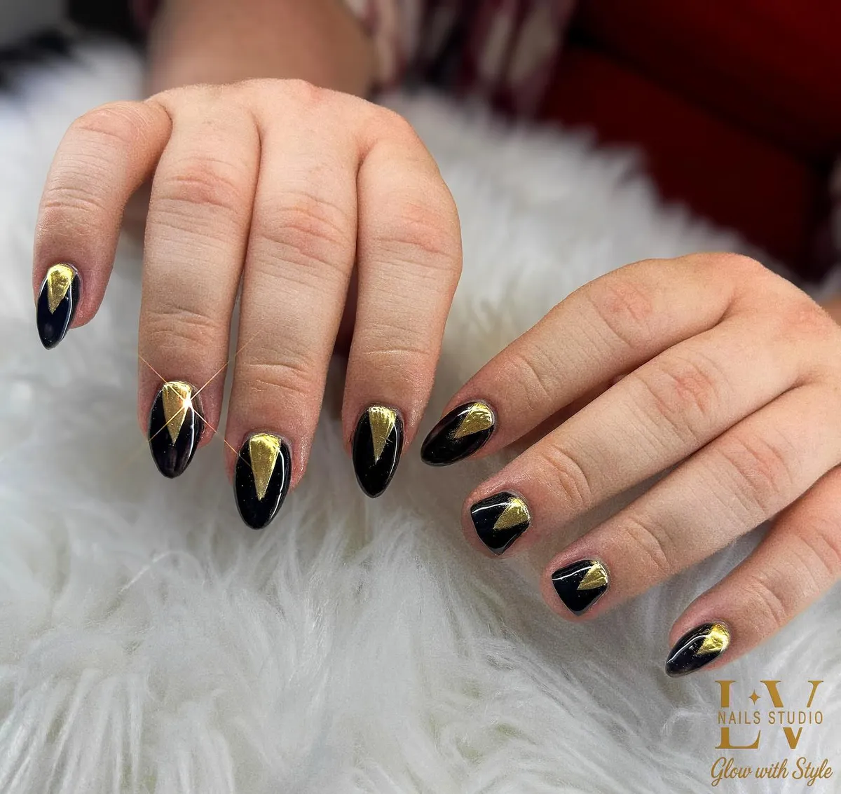 Glossy black nails with centered gold triangle accents