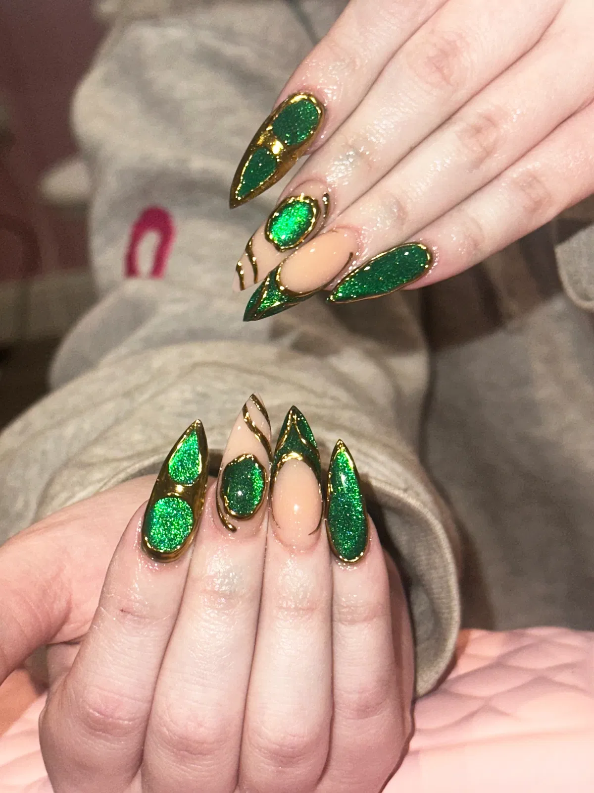Glittery green inlays bordered with gold on long pointed nails