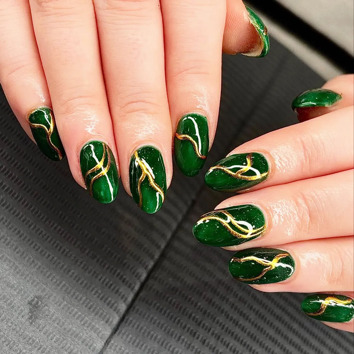 Deep green glossy nails with gold veining lines