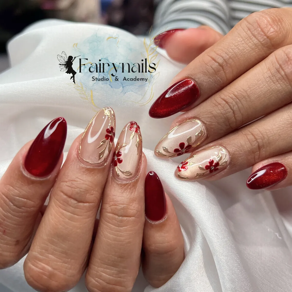 Deep red shimmer with nude floral nails and fine gold outlining