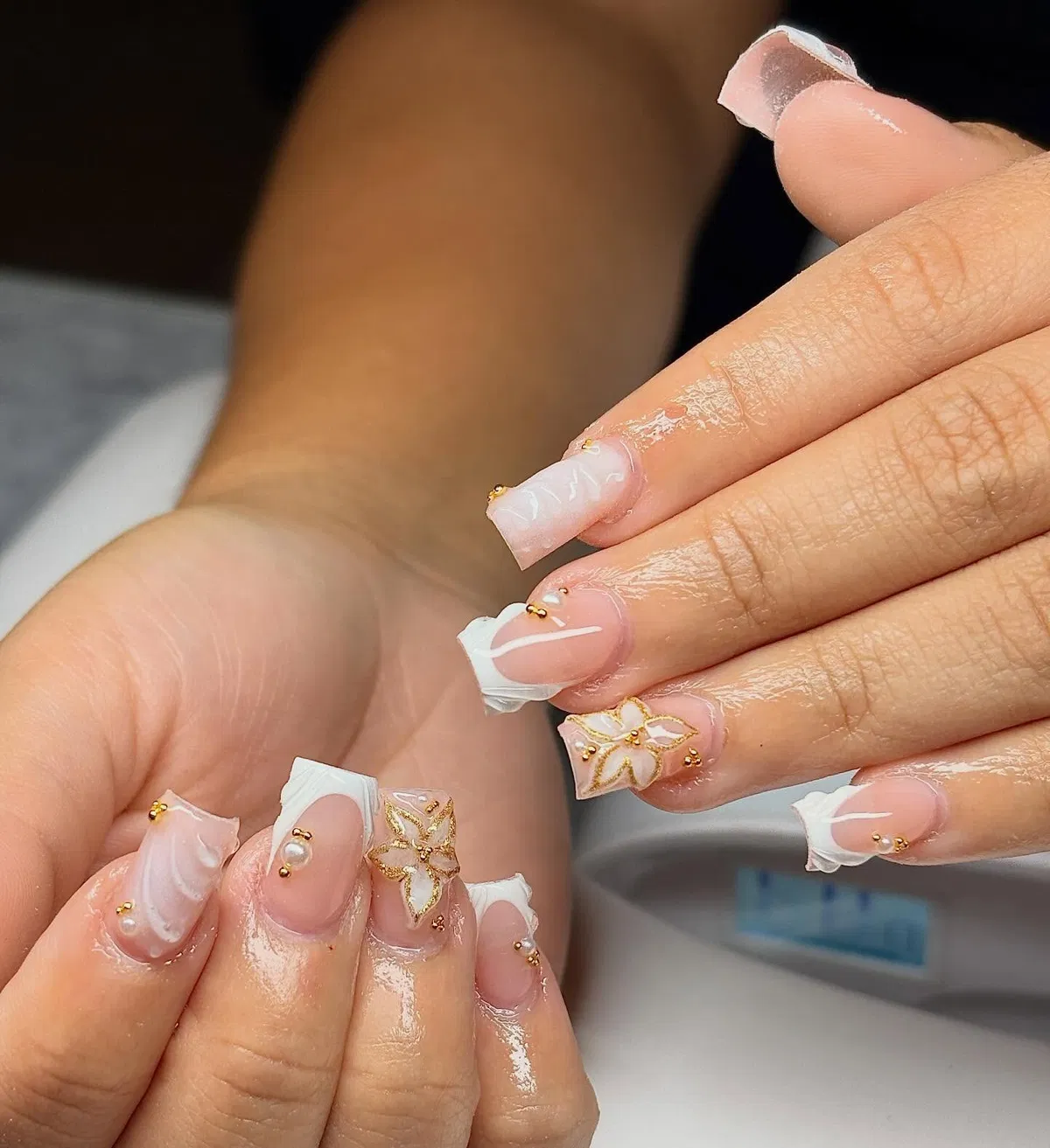 Square nude nails with sculpted white tips and gold floral line art