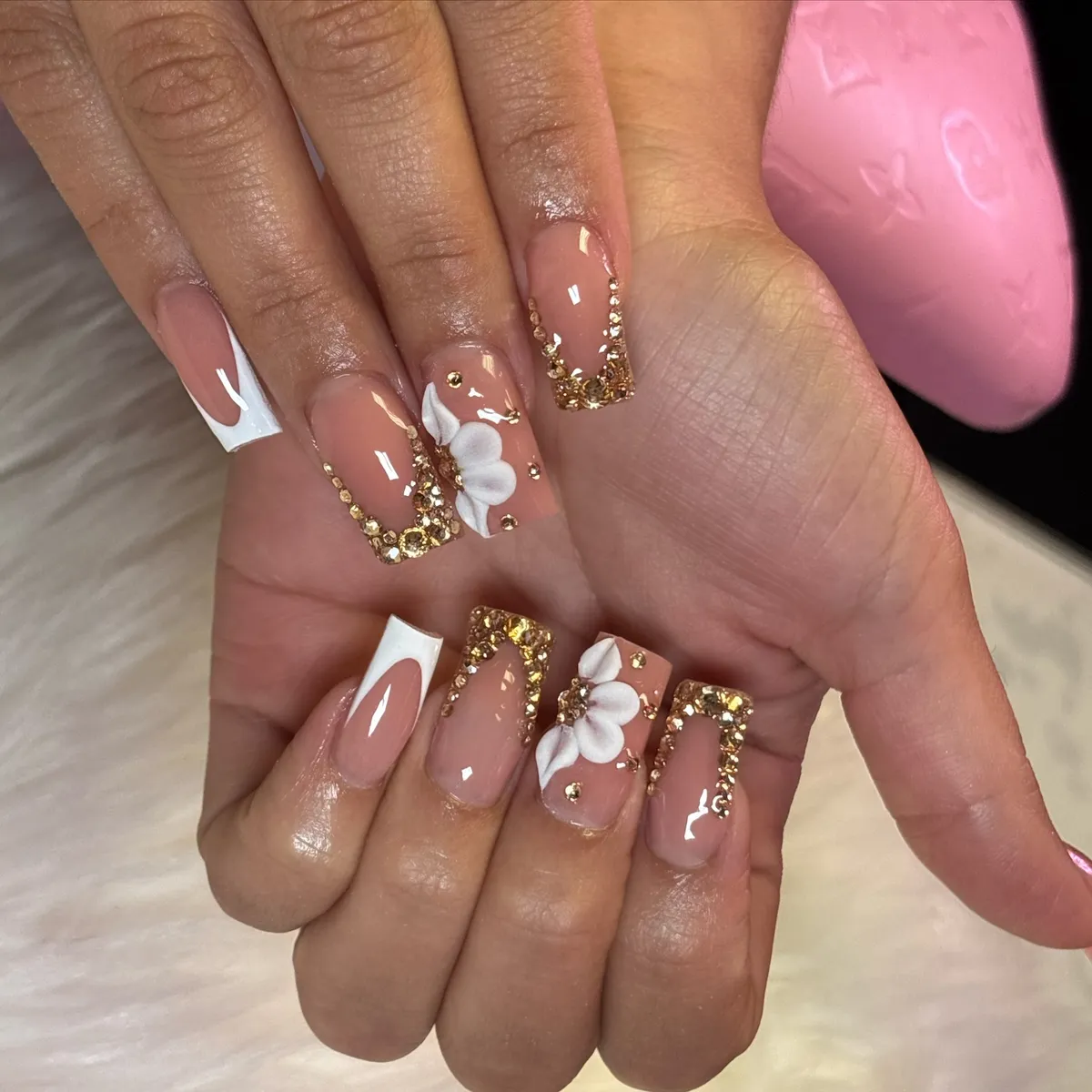Long square nude nails with white tips, gold rhinestone borders, and 3D flowers