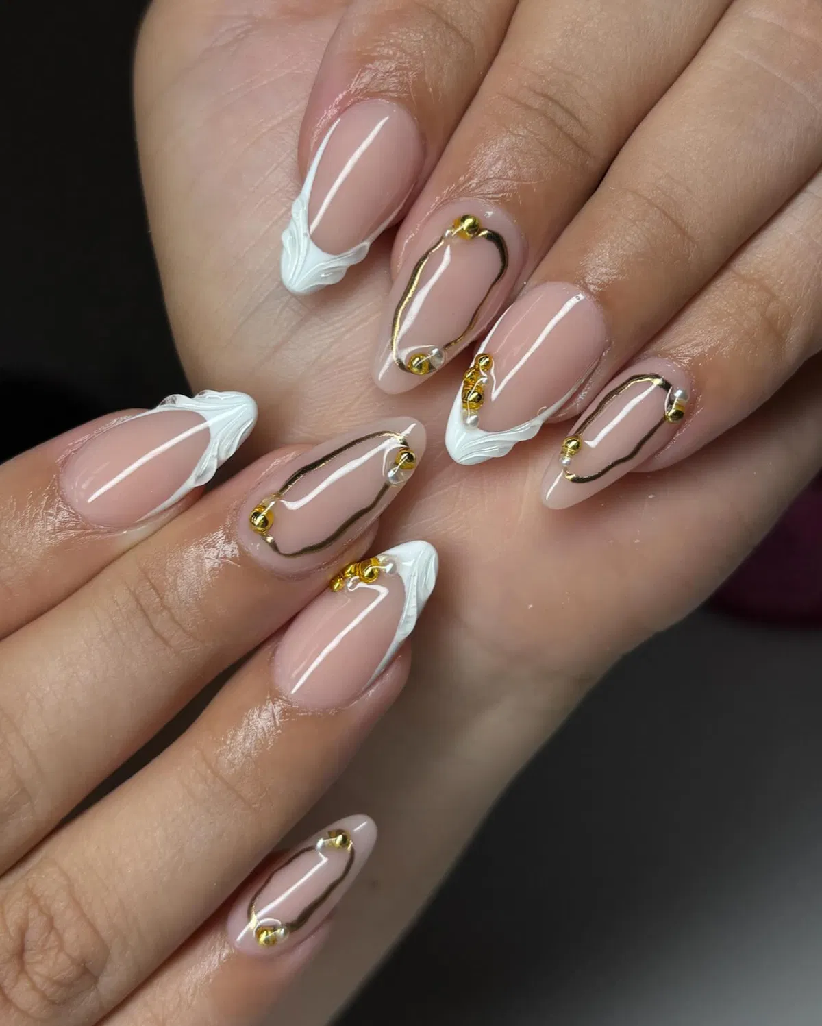 Nude almond nails with raised white tips and gold outline frames