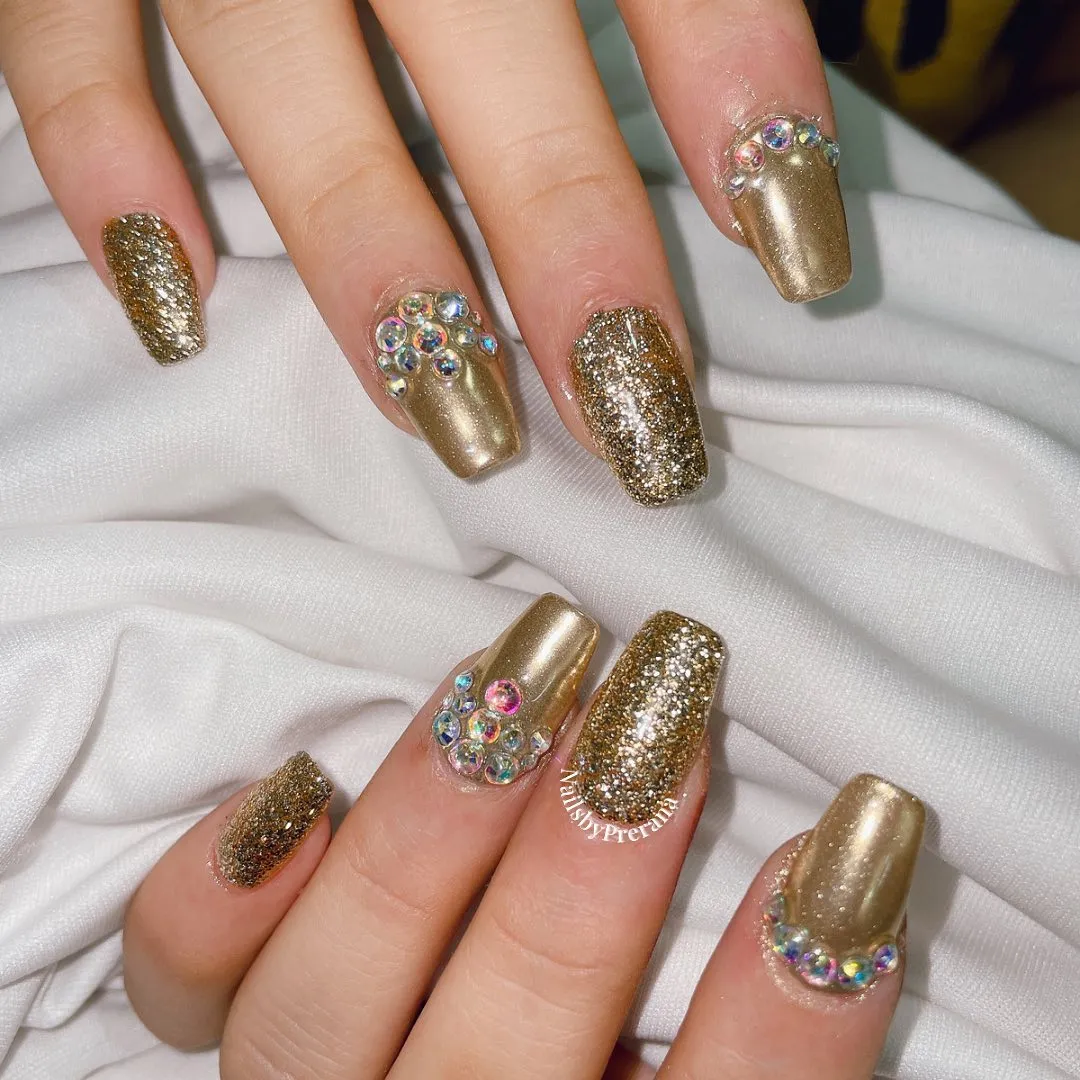 Gold glitter and metallic nails with iridescent gem clusters