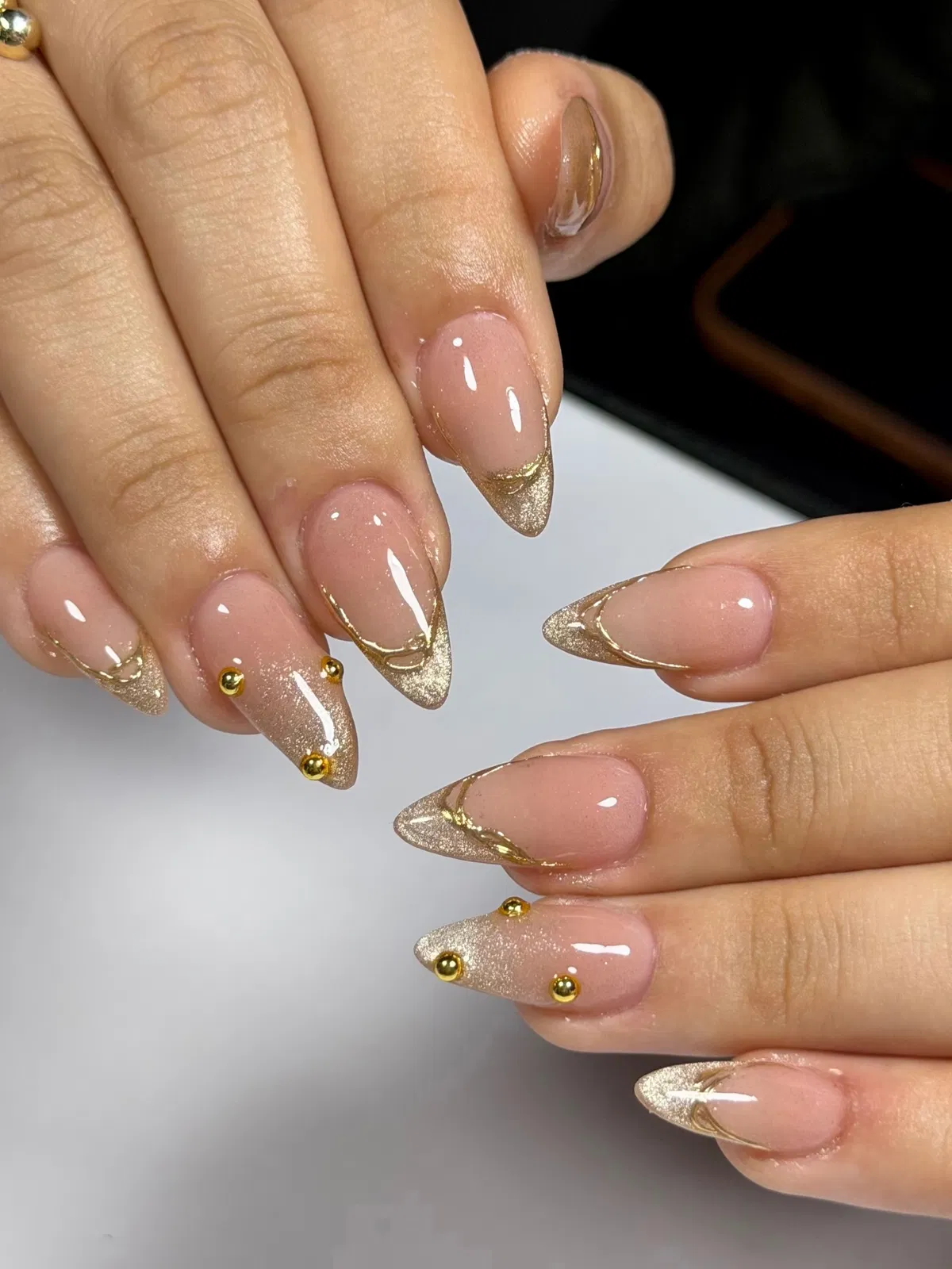 Nude almond French with gold glitter tips and studs