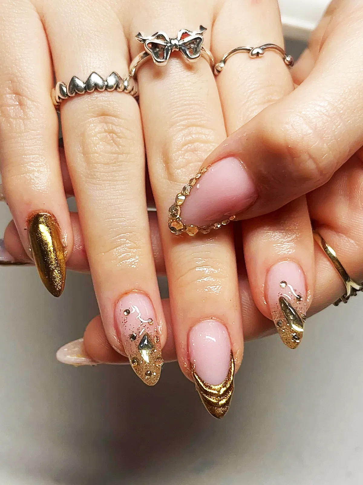 Nude stiletto nails with metallic gold tips and rhinestone edging