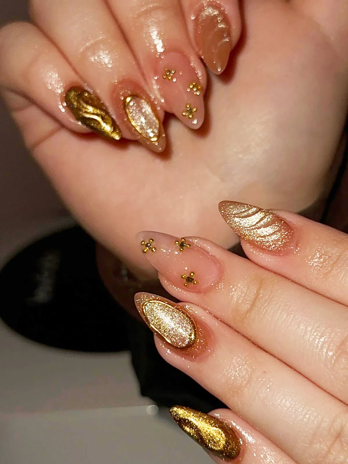 Gold glitter and nude stiletto nails with gold bead accents