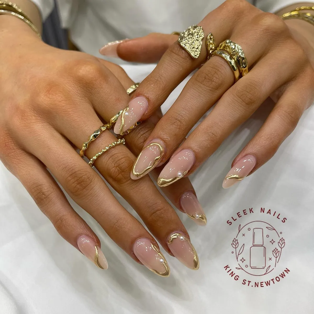 Minimal nude almond nails with thin gold edging and pearls