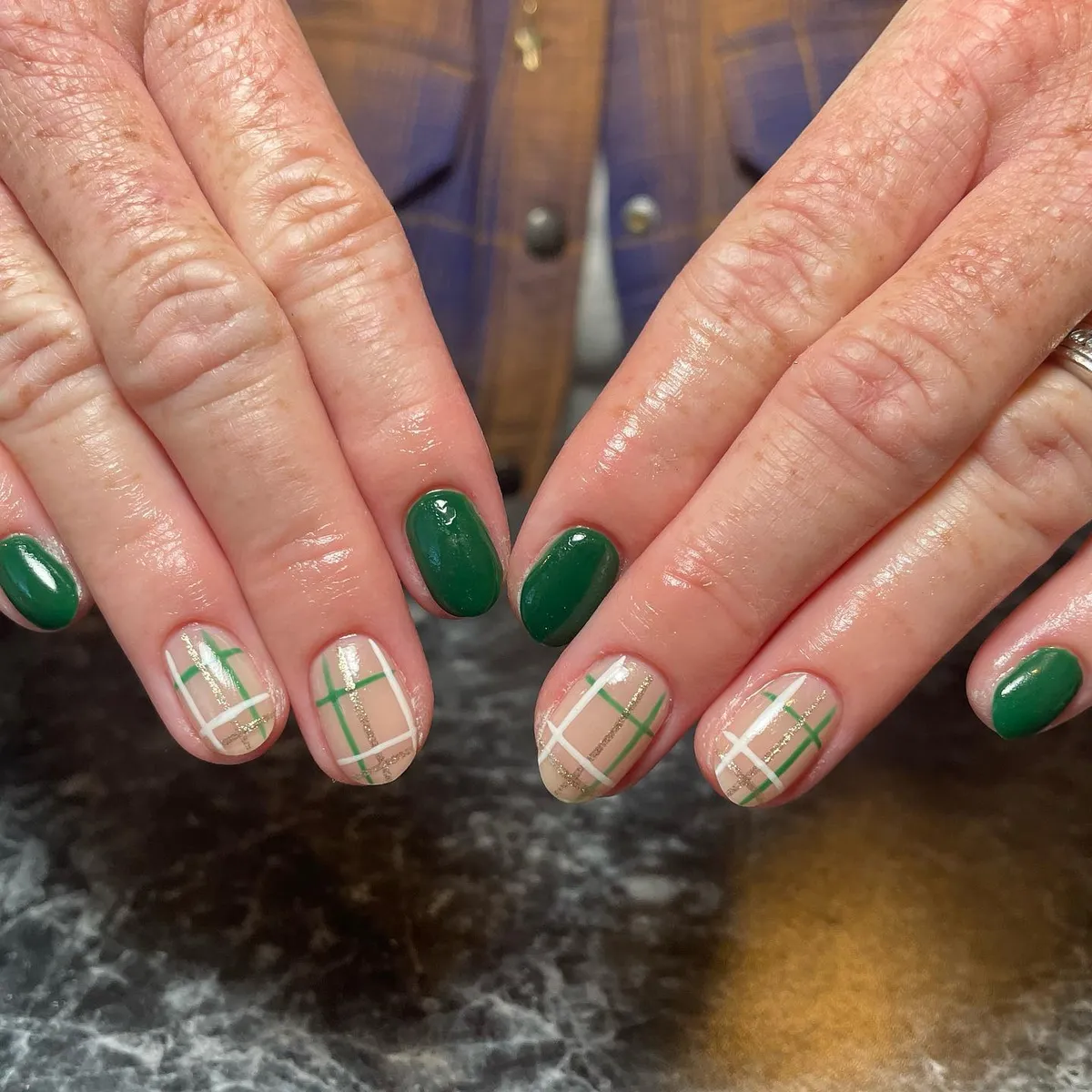 Short green nails with beige plaid accents and fine gold lines