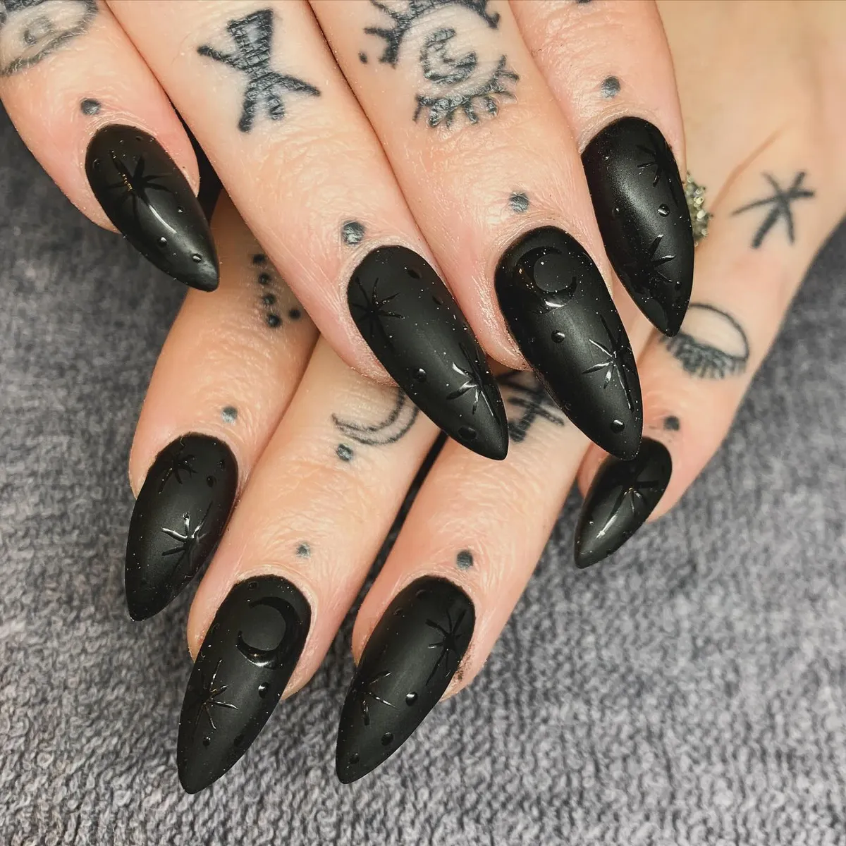 Matte black stiletto nails with raised celestial-style details