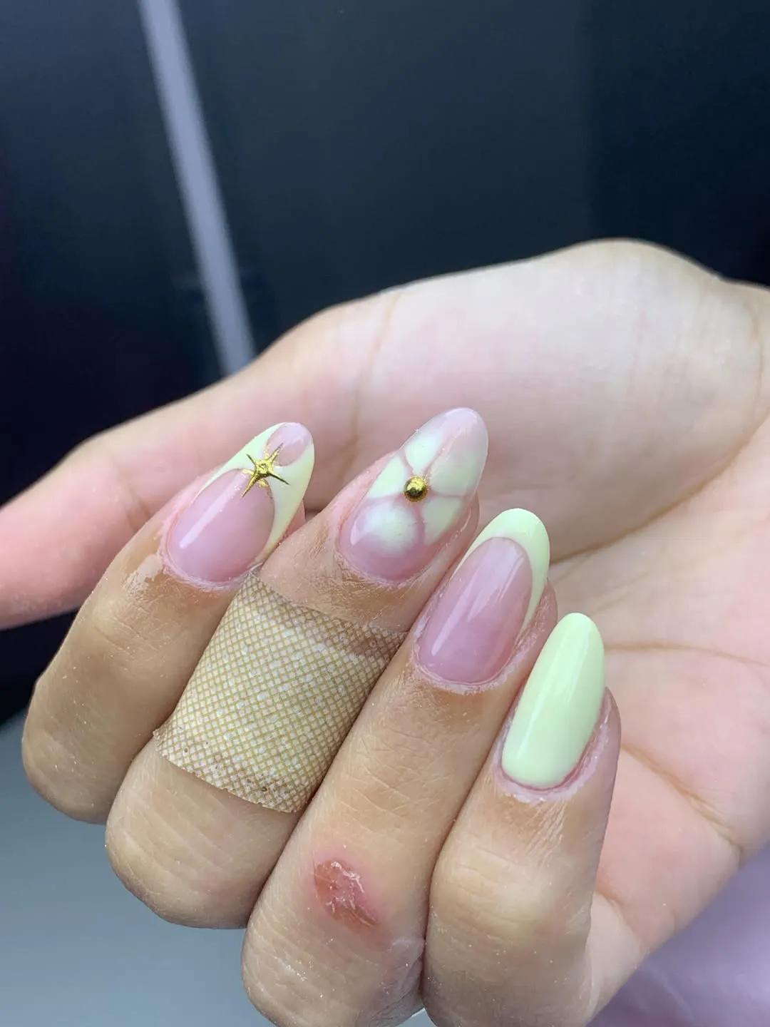 Pale yellow French tips with charms and a floral center stud