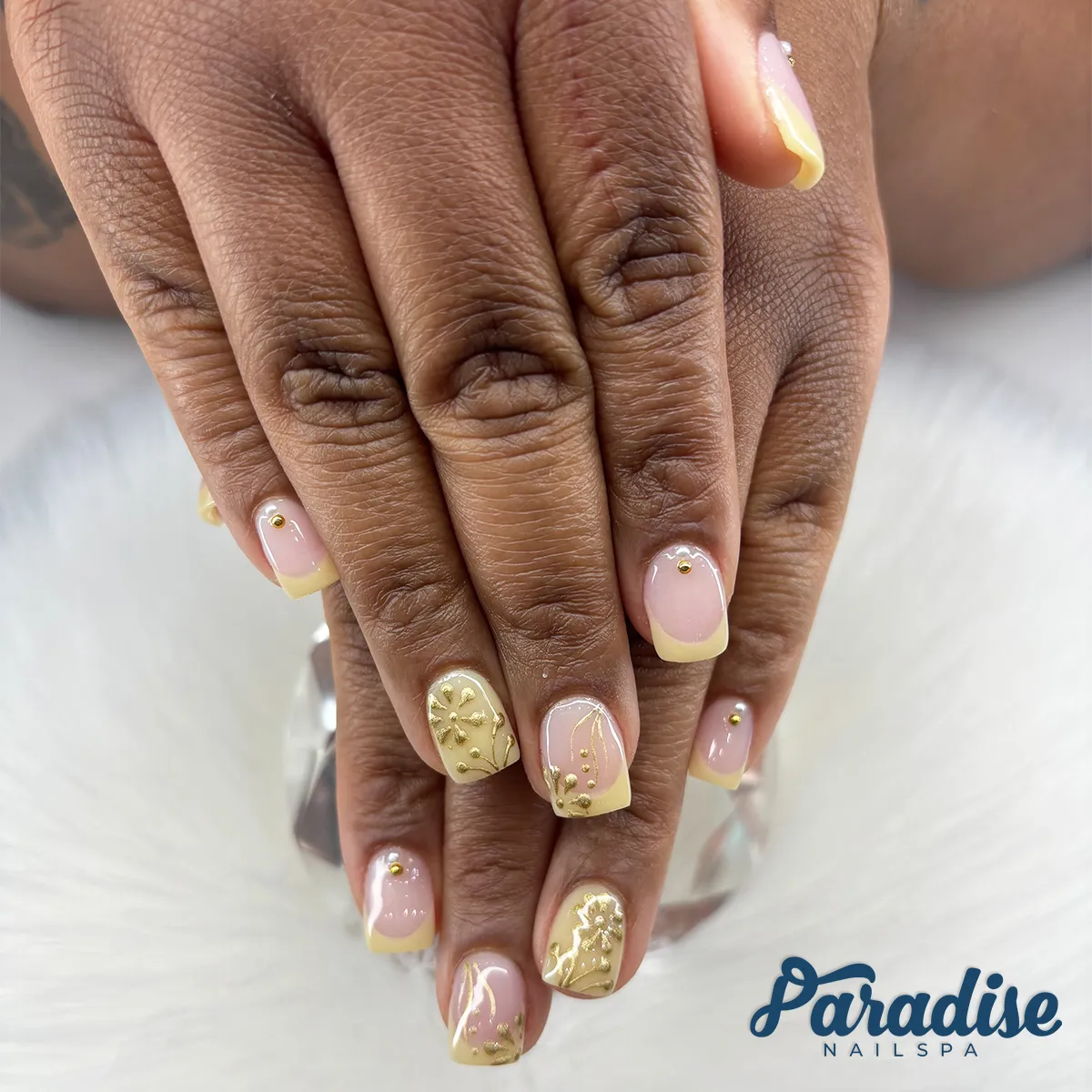 Pale yellow French tips with gold studs and gold embossed accents