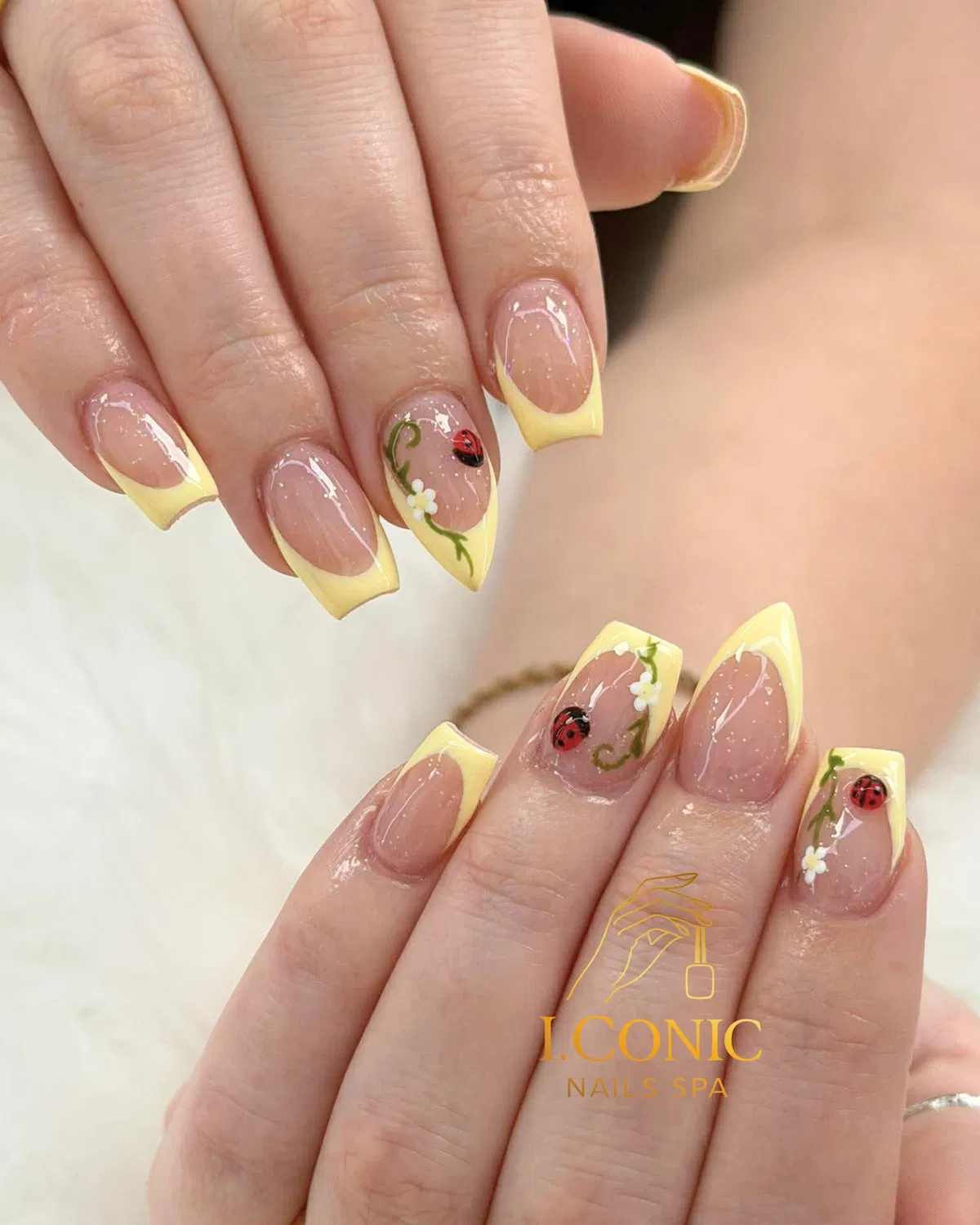 Pastel yellow French tips with ladybug and floral accents