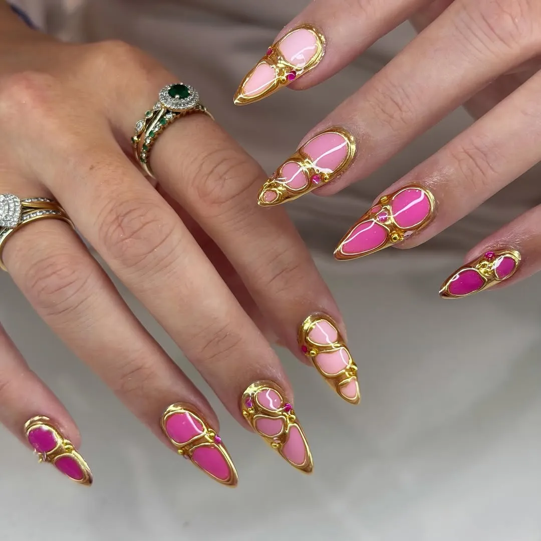 Raised gold framing over pink stiletto nails