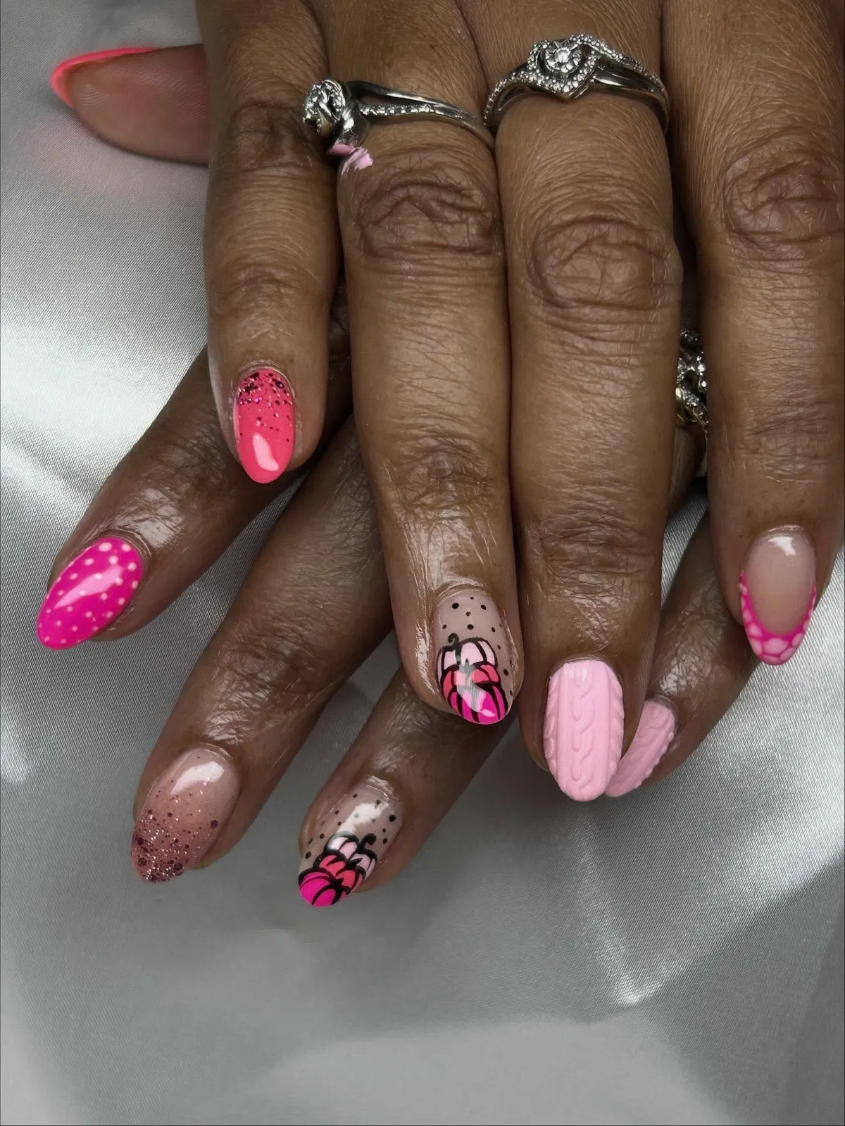 Mixed pink set with pumpkin art, dots, glitter, and a textured accent nail