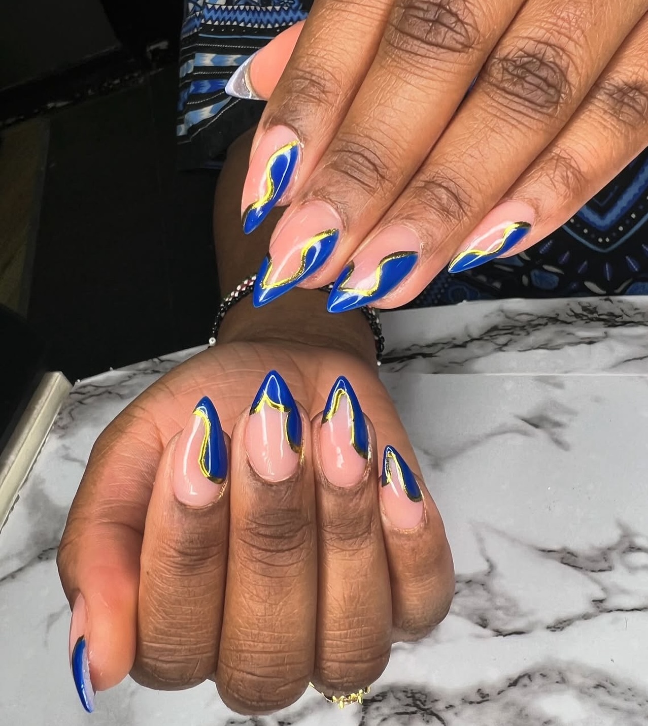 Wavy blue flames outlined in gold on nude base