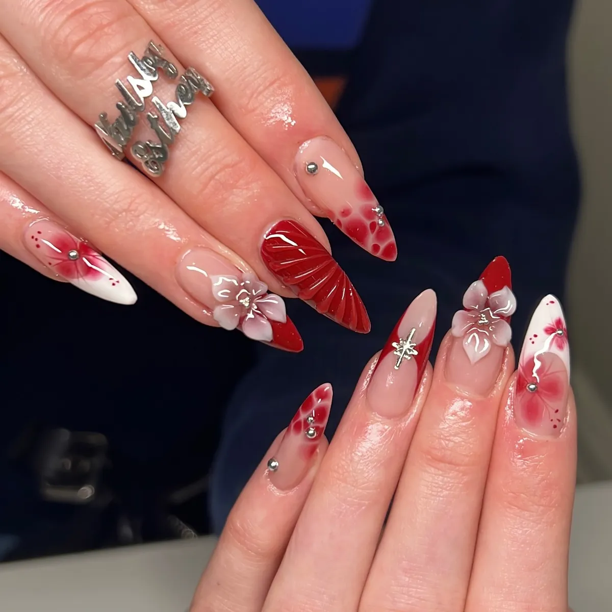 Red aura accents with 3D flowers, studs, and a textured deep-red nail
