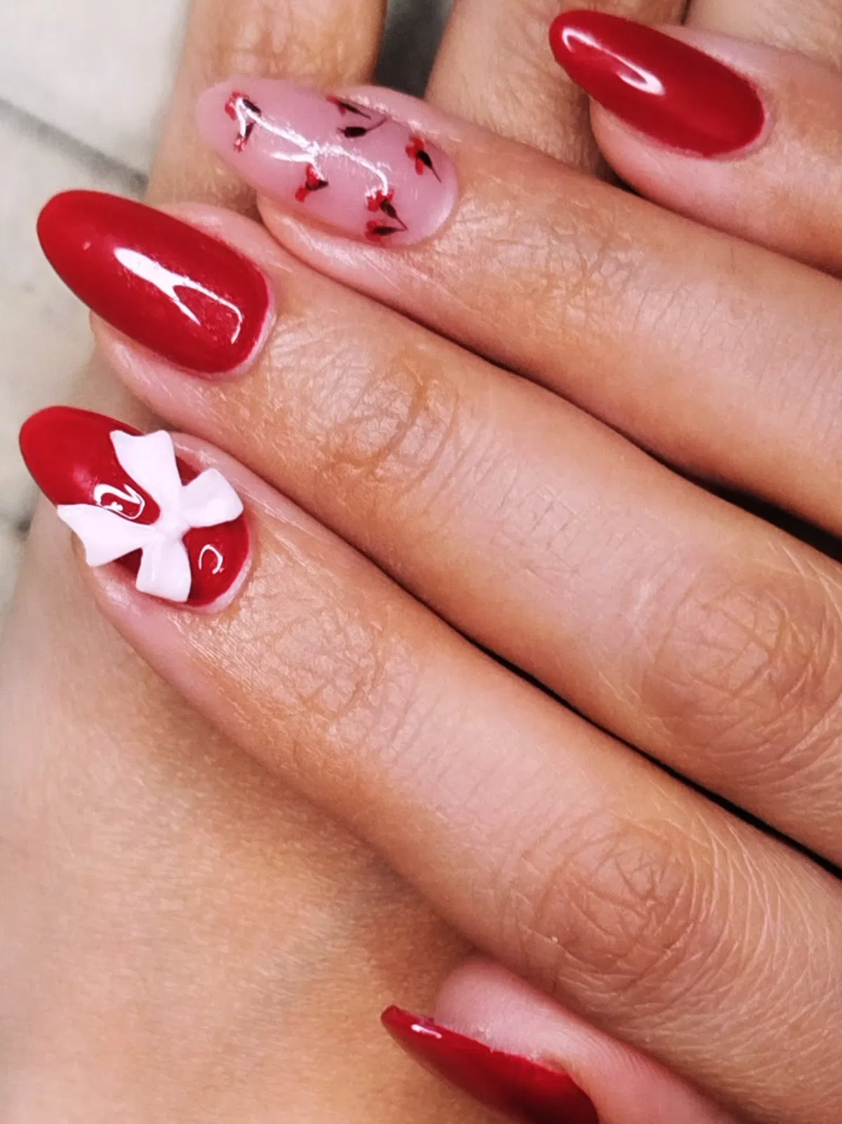 Bright red nails with a 3D white bow accent