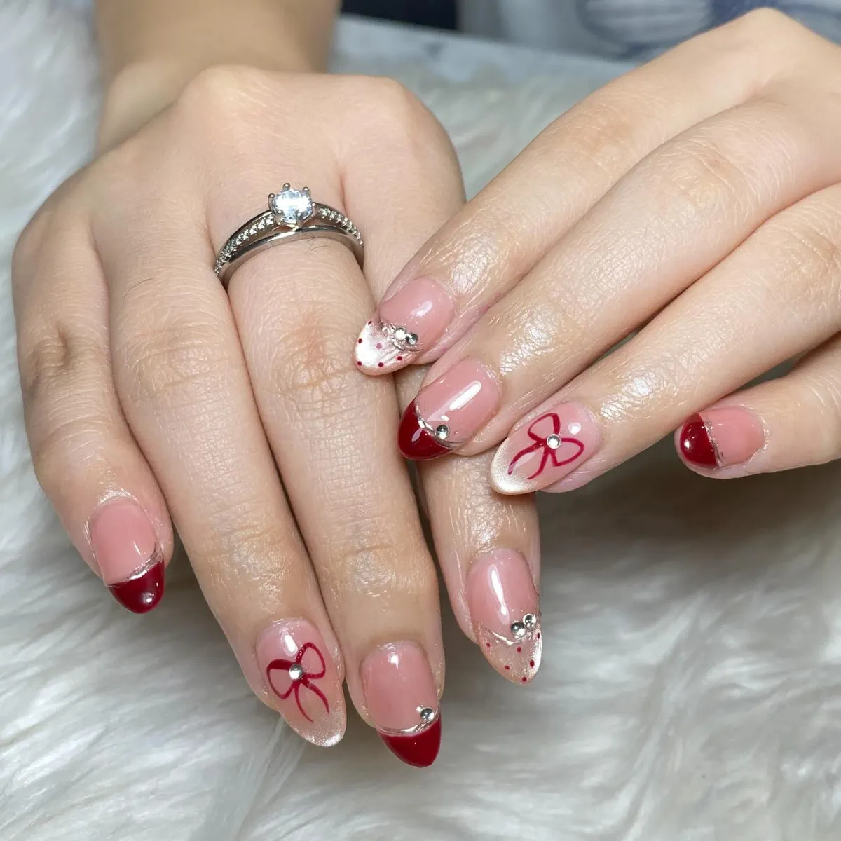 Nude Base with Deep Red French Tips, Bows, and Rhinestone Accents