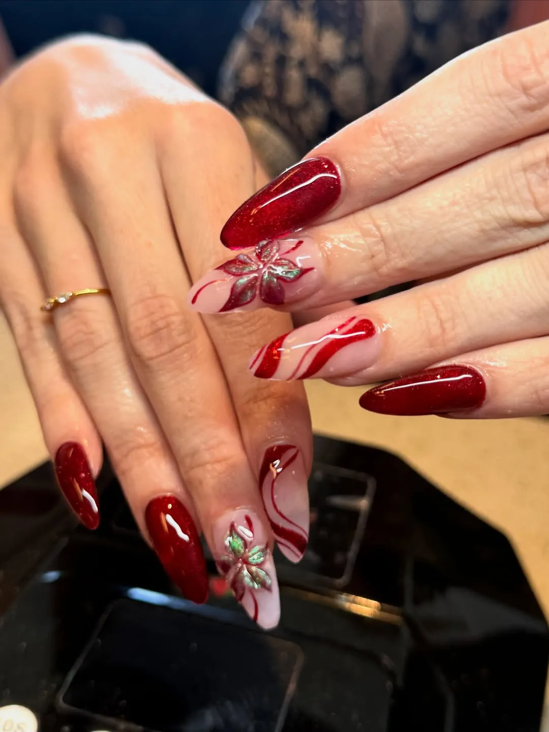 Deep red and nude nails with curved stripes and floral accents
