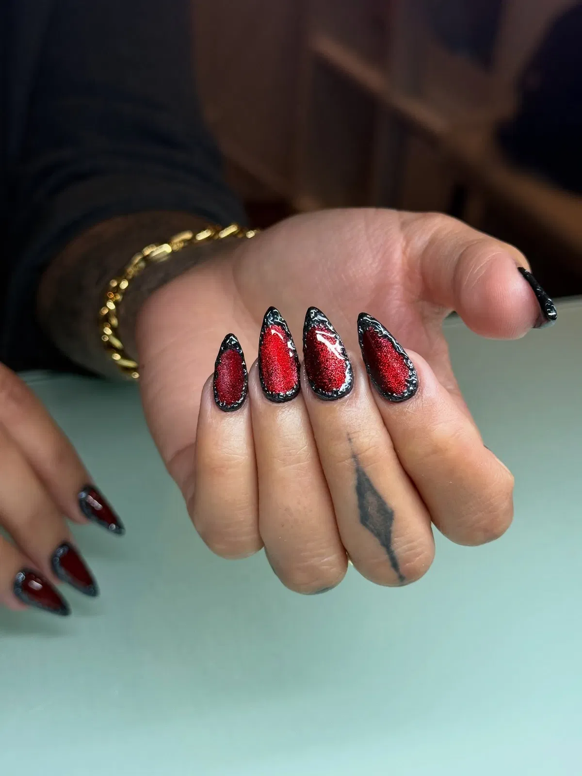 Red shimmer nails with black framed outline and silver dot accents