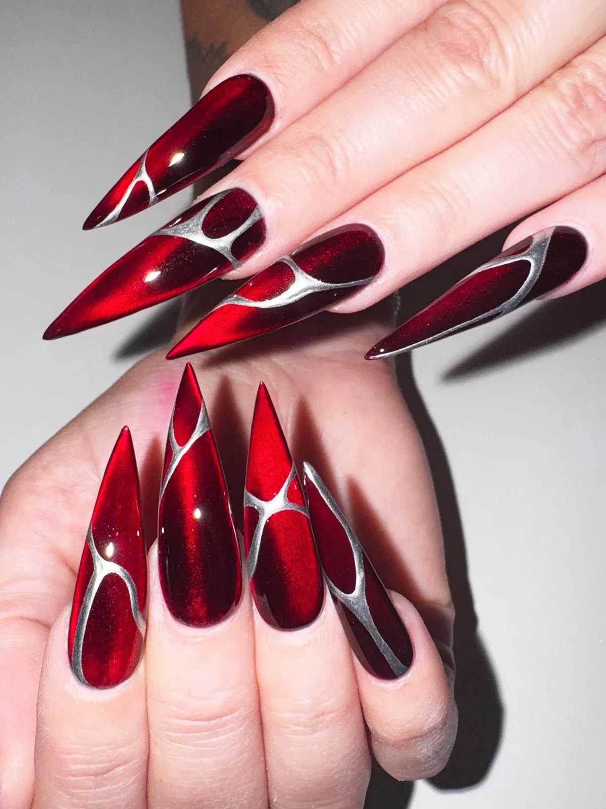 Ultra-long red stiletto nails with silver web-like linework