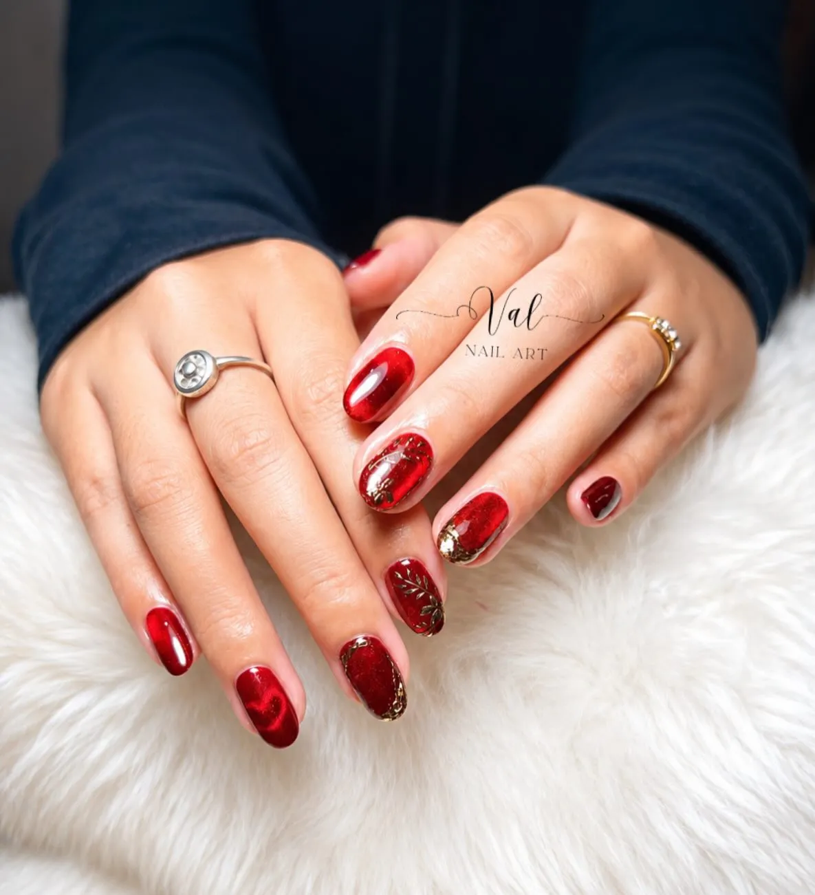 Glossy red nails with gold foil-like accents (watermarked)