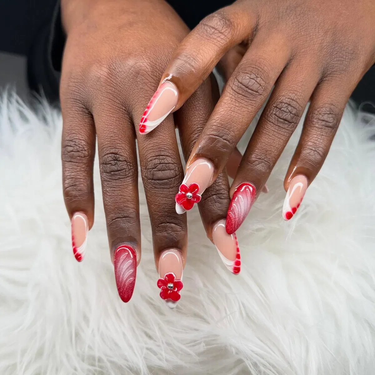 Nude almond nails with red-and-white tips and 3D red flowers