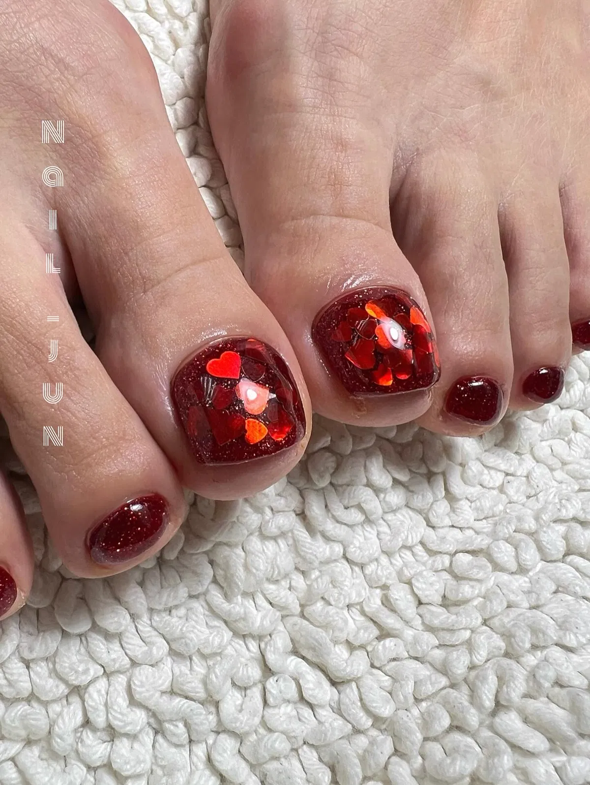Deep red glitter toes with heart-confetti big-toe accents