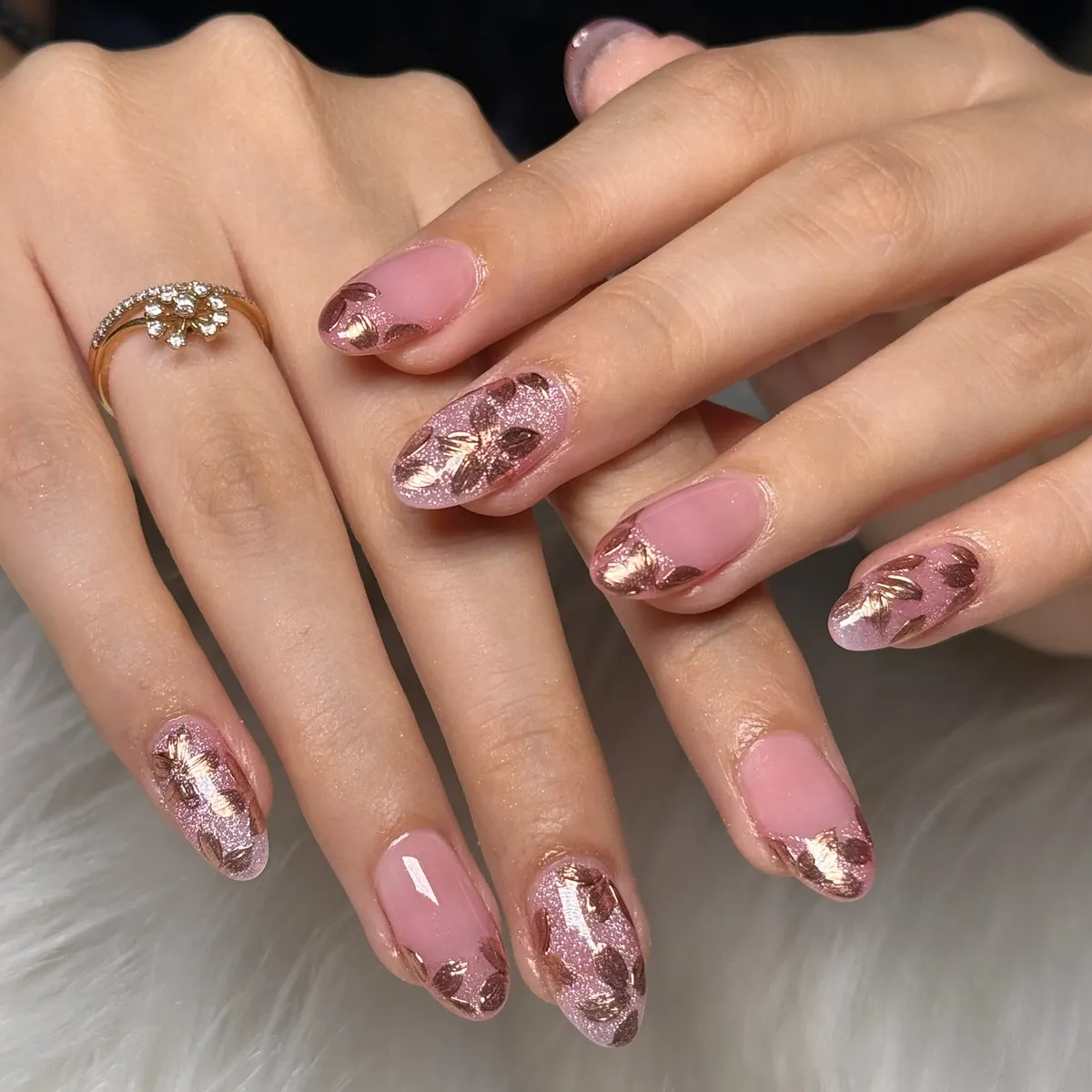 Pink nails with rose-gold glitter and metallic leaf/floral motifs (alternate view)