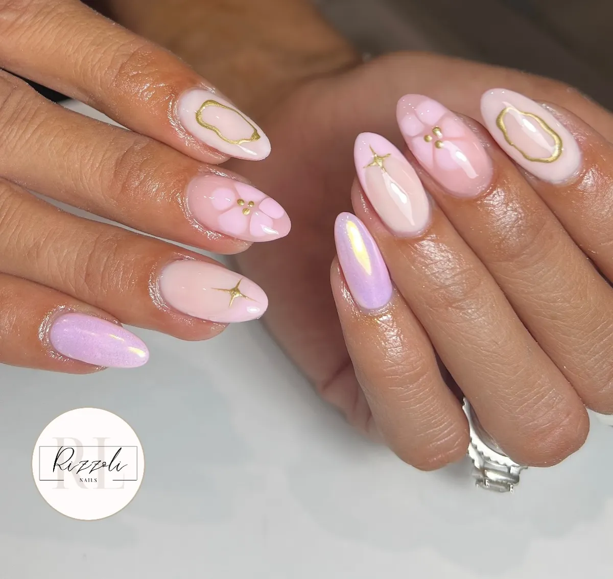 Pale pink and lavender glossy nails with gold starbursts