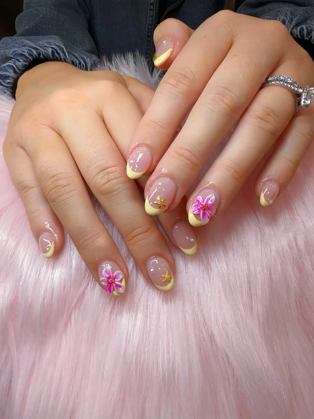 Pale yellow French tips with pink flowers and gold star accents